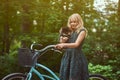 Portrait of a little blonde girl in a casual dress, holds cute spitz dog, in a park. Royalty Free Stock Photo