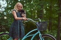 Portrait of a little blonde girl in a casual dress, holds cute spitz dog, in a park. Royalty Free Stock Photo