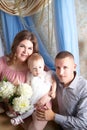 Portrait of a little blonde girl, plump chubby mother and big father. Family in studio during photo shoot