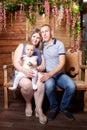 Portrait of a little blonde girl, plump chubby mother and big father. Family in studio during photo shoot