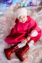 Portrait of little blonde smiling girl wears white beret, red boots, pink cloak and plays with toy candy. Christmas and New Year Royalty Free Stock Photo