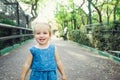 Portrait of little blondy toddler Girl Smiling at Camera. Happy kid walking outdoors in the park or zoo. Family recreation, leasur