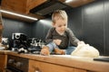 Portrait of little boy bake in kitchen at home. Baby toddler sitting on table with floury legs, touching dough. Cooking. Royalty Free Stock Photo