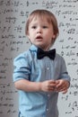 Portrait of the little boy in the blue shirt over the math background, high IQ, mathl mindset, child prodigy