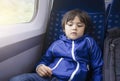 Portrait of little boy with bored face sitting alone on the train, Preschool kid traveling by train, Child with unhappy face not