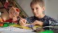 Portrait of little boy with brother sitting on kitchen and writing letter to Santa on Christmas. Royalty Free Stock Photo