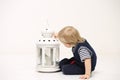 Portrait of a little boy with a candleholder in his hand, light background