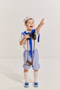 Portrait of little boy, child in image of seaman in vest posing with binoculars over grey background. Interesting Royalty Free Stock Photo