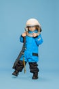 Portrait of little boy, child posing in astronaut costume over blue studio background. Fantastic game. Concept of