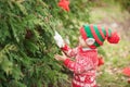 Portrait of a little boy in elf hat and red sweater near the christmas tree and holding decoration Royalty Free Stock Photo