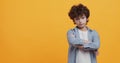 Portrait of little boy with folded arms expressing contempt or annoyance, looking at camera with condemnation