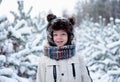 Portrait of a little boy in a fur hat with a smile in a snowy forest