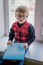 Little boy in glasses with book in library on window Royalty Free Stock Photo
