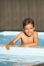 Portrait, little boy and happiness in swimming pool, resort and lodge for recreation, summertime and relaxation. Male Royalty Free Stock Photo