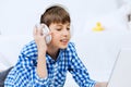 Portrait of little boy listening music from laptop through headphones while lying on hardwood floor Royalty Free Stock Photo