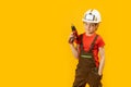 Portrait of little boy pretends to drill wall with drill, yellow isolated background. Boy teenager as builder worker. Copy space,