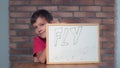 Child sitting at the desk holding flipchart with lettering fly o Royalty Free Stock Photo