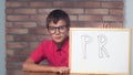 Child sitting at the desk holding flipchart with lettering pr on