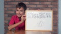 Child sitting at the desk holding flipchart with lettering signa