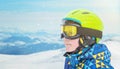 Portrait of a little boy in skier suit, halmet and glasses on ski resort mountain peak Royalty Free Stock Photo