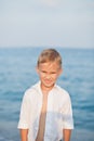 Portrait with little boy standing on the beach with blurry background by the sea