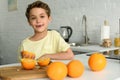 portrait of little boy standing at counter with fresh oranges in kitchen Royalty Free Stock Photo