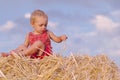 Portrait of little boy in a summer hat sitting on a haystack in a field of wheat Royalty Free Stock Photo