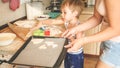 Portrait of cute little boy with young mother baking cookies on baking pan at kitchen Royalty Free Stock Photo