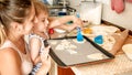 Portrait of cute little boy with young mother baking cookies on baking pan at kitchen Royalty Free Stock Photo
