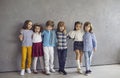 Portrait of little boys and girls having fun together standing against the backdrop of a gray wall. Royalty Free Stock Photo