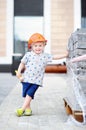 Portrait of little builder in hardhats with hammer working outdoors