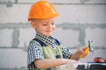 Portrait of little builder in hardhats with instruments for renovation on construction. Builder boy, carpenter kid with Royalty Free Stock Photo