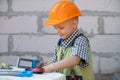 Portrait of little builder in hardhats with instruments for renovation on construction. Builder boy, carpenter kid with Royalty Free Stock Photo