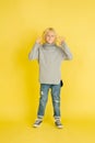 Portrait of little caucasian boy with bright emotions isolated on yellow studio background Royalty Free Stock Photo