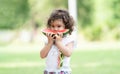 Portrait of little Caucasian cute girl holding sliced watermelon and enjoy eating or biting fresh fruit while picnic at park. Royalty Free Stock Photo