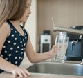 Portrait of a little caucasian girl gaining a glass of tap clean water. Kitchen faucet. Cute curly kid pouring fresh water Royalty Free Stock Photo