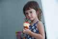 Portrait of little Caucasian girl holding and eating a big red apple in her hand