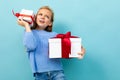 Portrait of little caucasian girl with long brow hair in blue hoody holds a white boxes with gifts isolated on blue Royalty Free Stock Photo