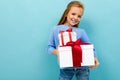 Portrait of little caucasian girl with long brow hair in blue hoody holds a white boxes with gifts isolated on blue Royalty Free Stock Photo