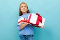 Portrait of little caucasian girl with long brow hair in blue hoody holds a white boxes with gifts isolated on blue Royalty Free Stock Photo