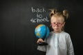 Elementary school student holding the globe on the black school board background Royalty Free Stock Photo