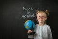 Elementary school student holding the globe on the black school board background Royalty Free Stock Photo