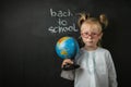 Portrait of little caucasian girl wearing glasses. Elementary school student holding the globe Royalty Free Stock Photo