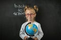 Portrait of little caucasian girl wearing glasses. Elementary school student holding the globe Royalty Free Stock Photo