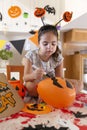 Little caucasian toddler girl painting a balloon to decorate her house during Halloween celebration
