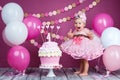 Portrait of a little cheerful birthday girl with the first cake. Eating the first cake. Smash cake