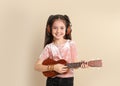 Portrait of little cheerful girl with headphones playing guitar Royalty Free Stock Photo