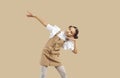 Little girl in casual beige denim pinafore dress dancing on beige studio background Royalty Free Stock Photo