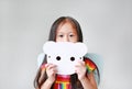 Portrait of little child girl holding blank white animal paper mask fronting her face on white background. Idea and concept for
