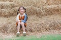 Portrait of little child girl and warm clothes sitting on pile of straw on a winter season